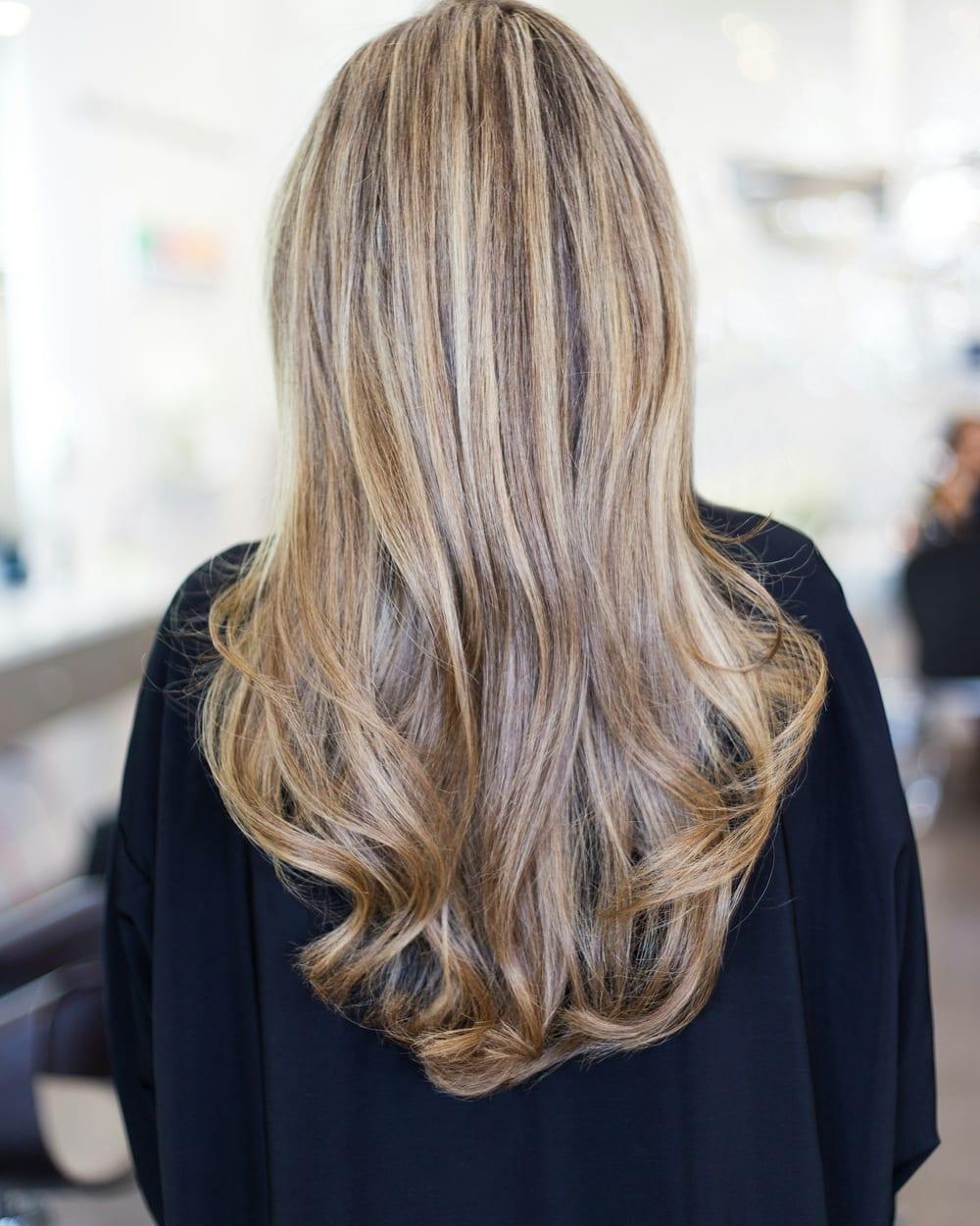 Cabelo liso e comprido visto de costas, com mechas loiras finas espalhadas sobre a base castanho claro.