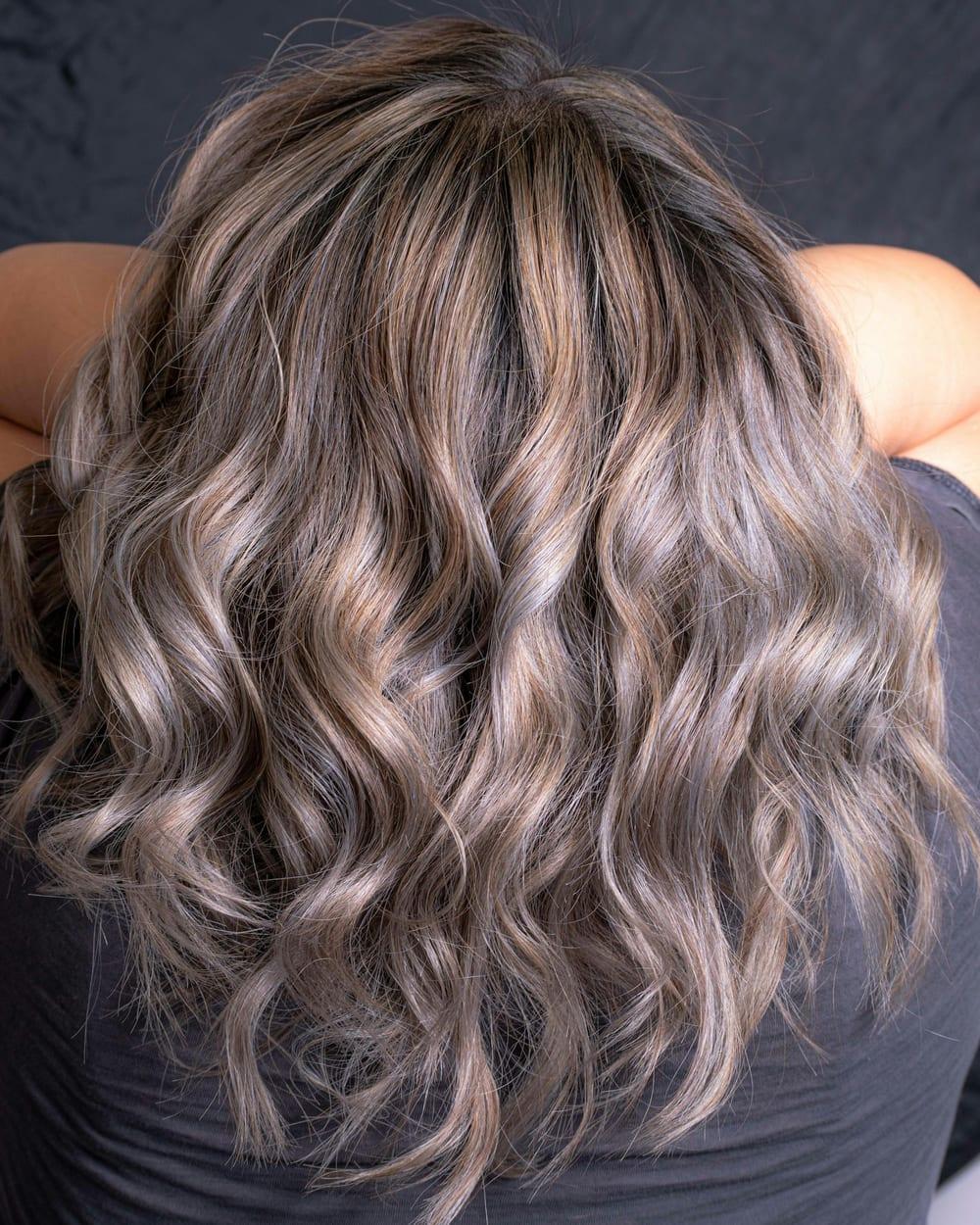 Cabelo ondulado na altura dos ombros, visto de costas, em loiro acinzentado com reflexo perolado.