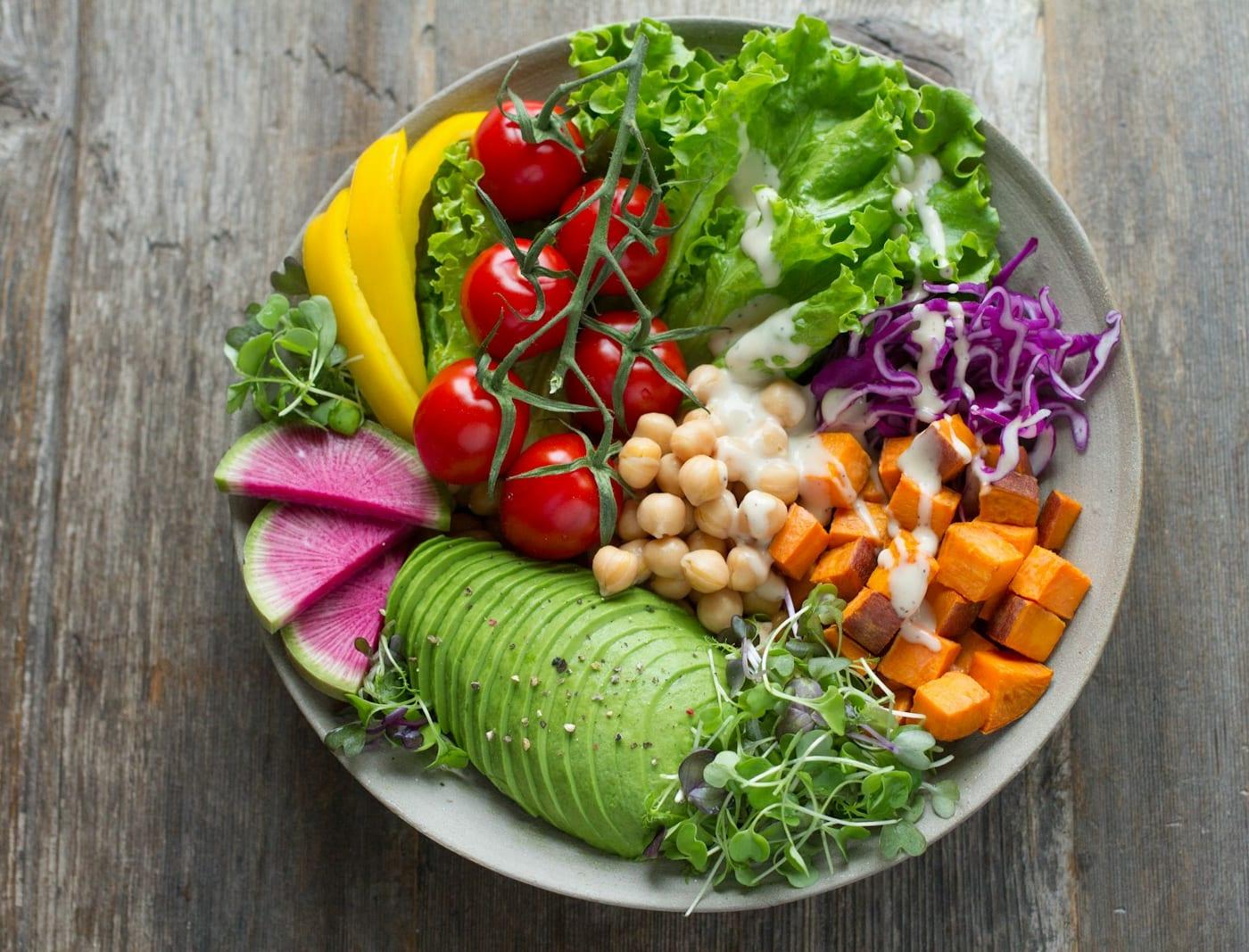 Prato com grão-de-bico, abacate, tomate, abóbora assada, repolho roxo, rabanete e folhas