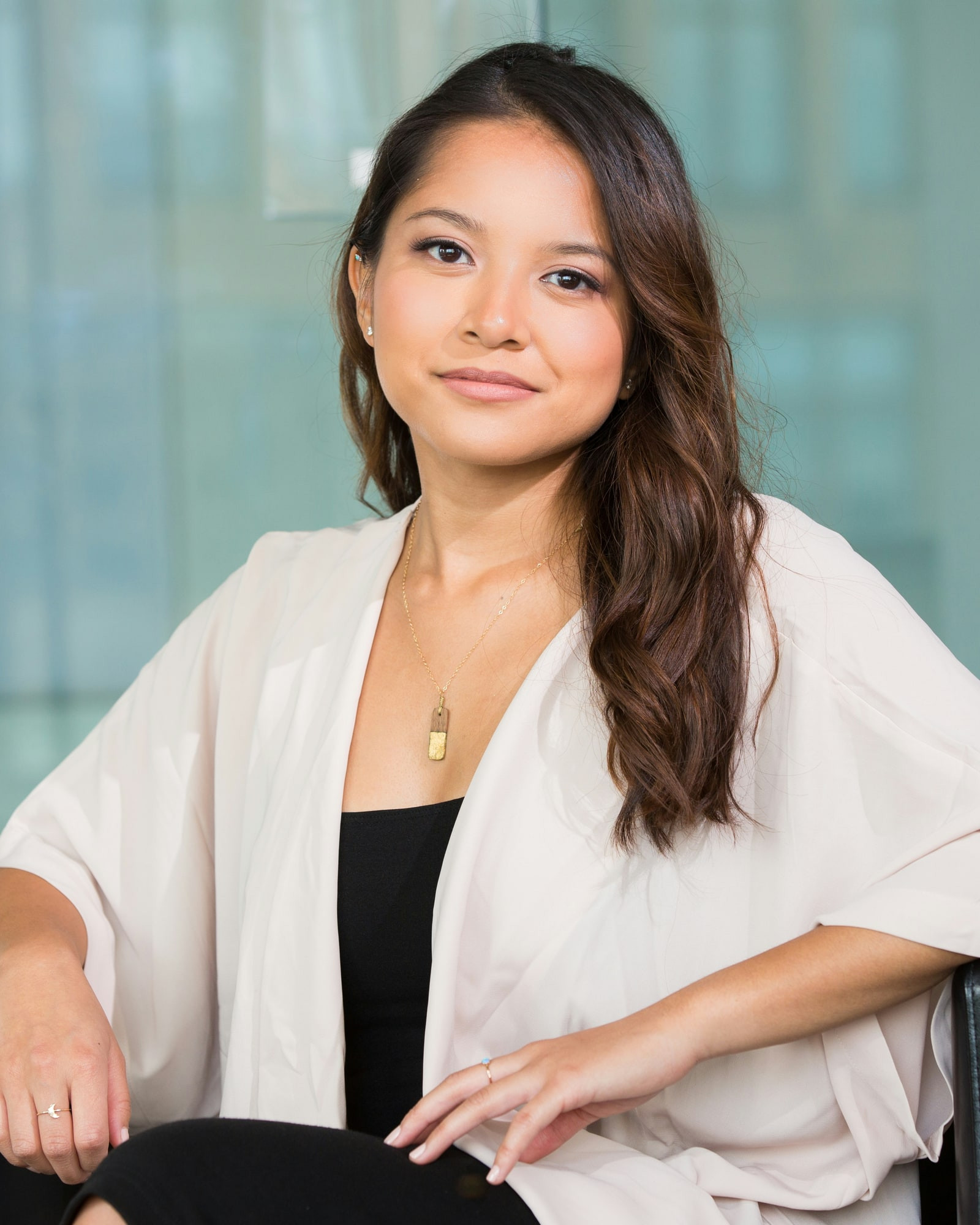 Lívia Tanaka, nutricionista, sentada numa poltrona de couro preto no consultório, de blusa clara, olhando para a câmera
