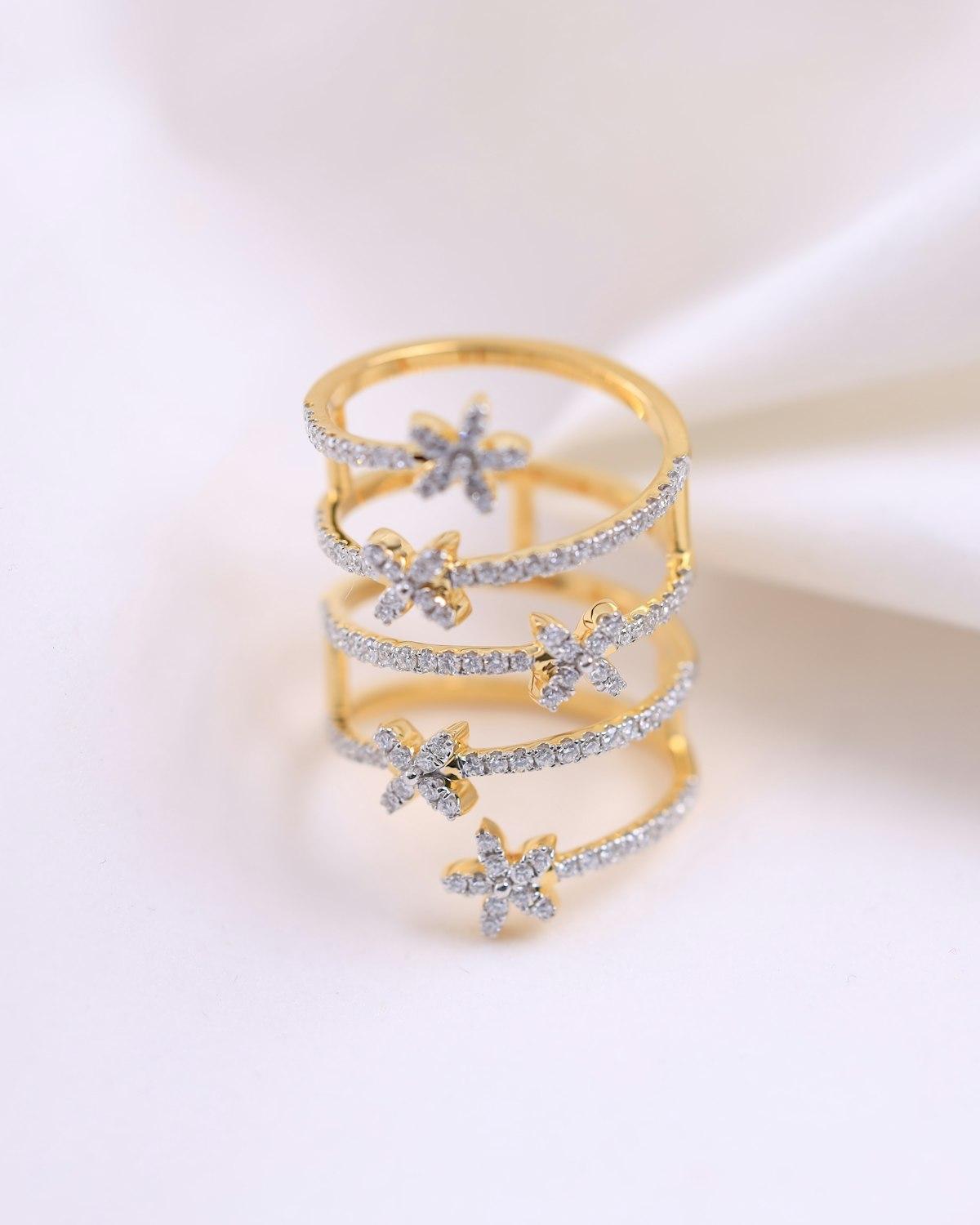 Anel dourado em espiral com flores de zircônia, sobre tecido branco